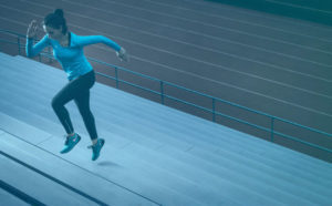 This image shows a person wearing blue and black training gear, performing stair sprints. Sprinting up and down stairs as fast as you can is a great way to burn calories and improve strength in your legs. St Albans Personal Training will help you improve your strength and endurance using similar exercises and workouts so you can run faster for longer.